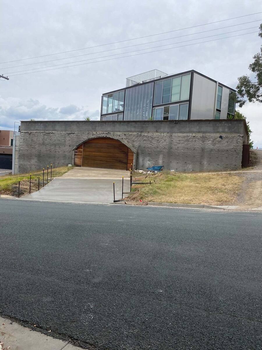 Finished concrete driveway in front of a feature shotcrete wall and modern home
