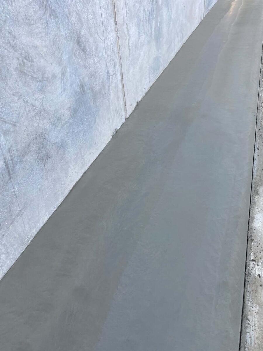 Fresh concrete footpath poured beside a rendered wall on a Victorian job