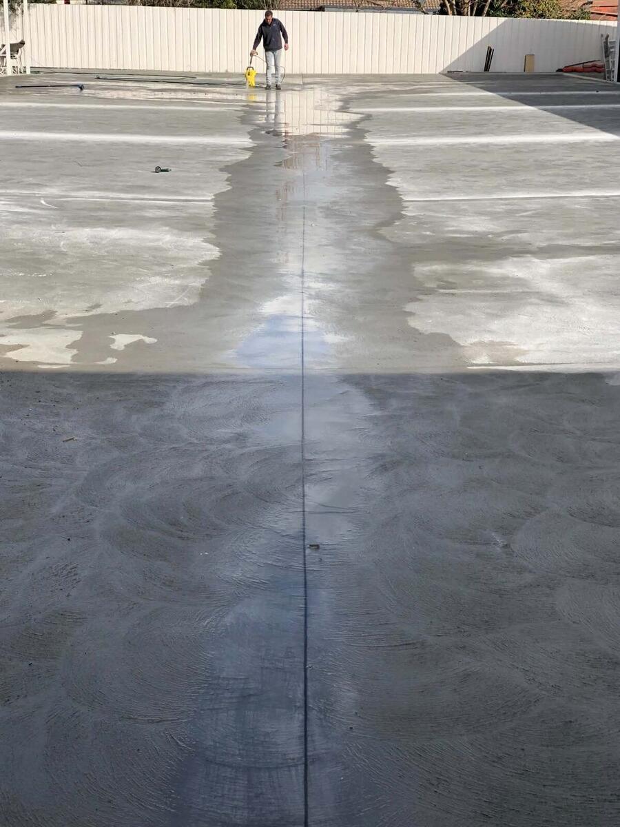 Concreter spraying sealer on a large burnished concrete slab