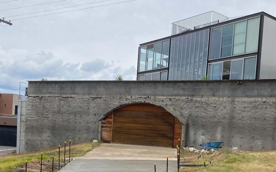 Finished concrete driveway in front of a feature shotcrete wall and modern Victorian home