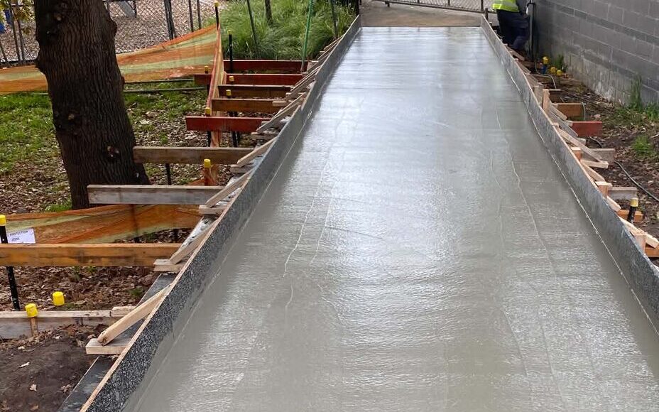 Freshly poured concrete footpath beside a building on a Victorian job